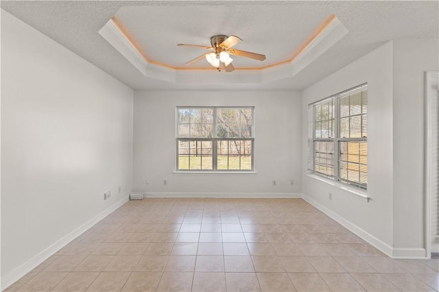 unfurnished room featuring a textured ceiling, a tray ceiling, baseboards, and ornamental molding