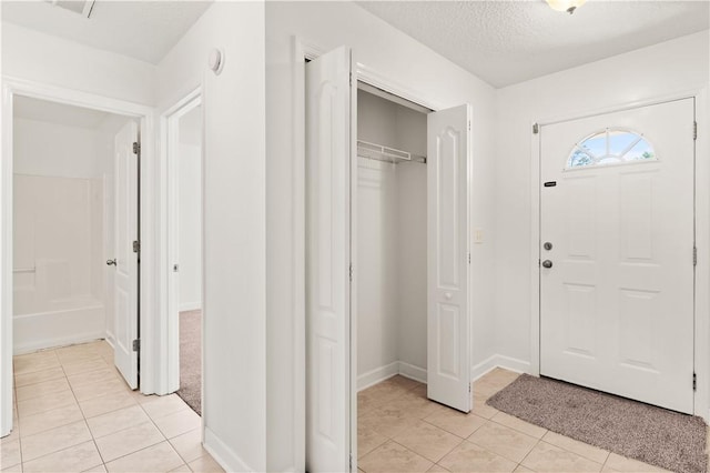 entryway featuring light tile patterned flooring, baseboards, and a textured ceiling