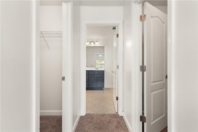 corridor featuring baseboards and light carpet