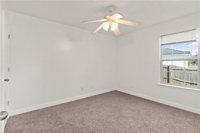 carpeted spare room with a ceiling fan and baseboards