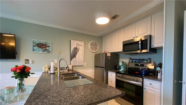 kitchen with visible vents, a sink, white cabinetry, stainless steel appliances, and crown molding