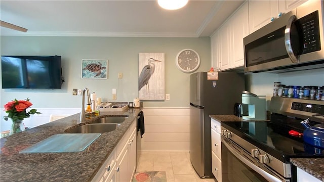 kitchen featuring dark stone countertops, appliances with stainless steel finishes, sink, white cabinetry, and ornamental molding