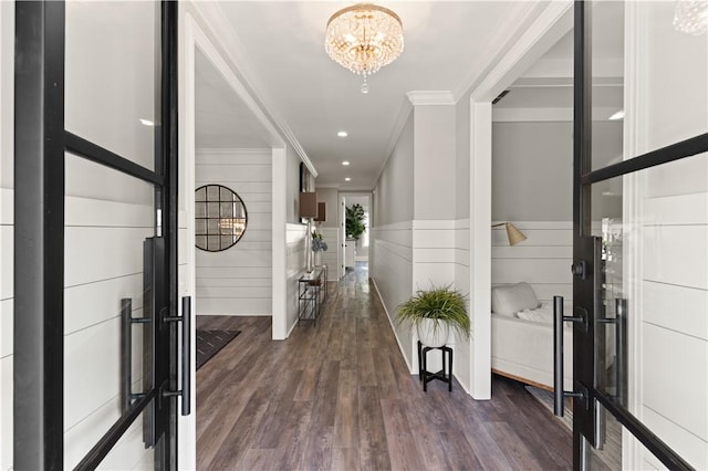 foyer entrance with a wainscoted wall, dark wood finished floors, ornamental molding, recessed lighting, and an inviting chandelier