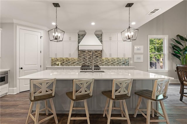 kitchen featuring a sink, visible vents, an inviting chandelier, and custom range hood