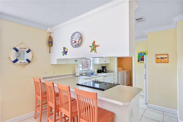 kitchen featuring ornamental molding, a breakfast bar, light countertops, washing machine and clothes dryer, and dishwasher