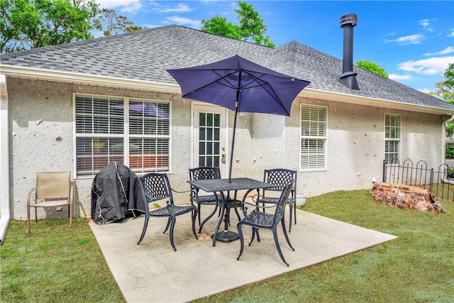 back of house with a lawn, a patio, a shingled roof, and stucco siding