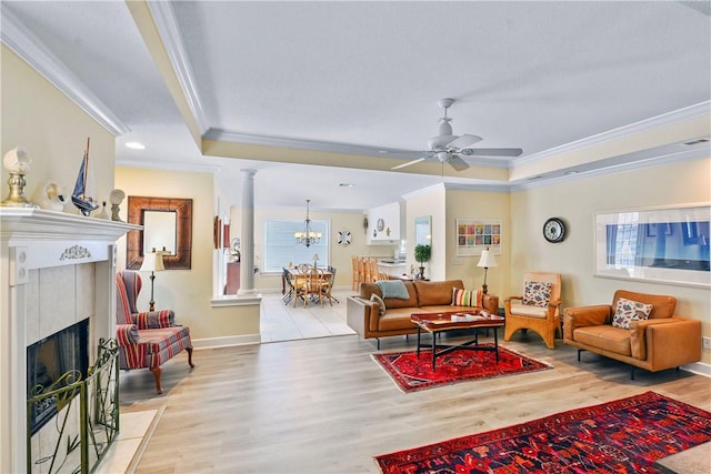 living room featuring ornamental molding, a raised ceiling, light wood-style flooring, and decorative columns