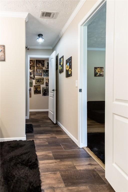 5618 Bowen Rd, Blackshear, GA 31516 - hall with dark wood finished floors, ornamental molding, and a textured ceiling