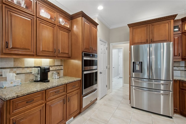 kitchen featuring stainless steel appliances, light stone counters, crown molding, decorative backsplash, and light tile patterned floors