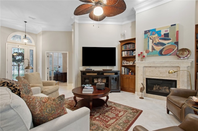 living room featuring ceiling fan, ornamental molding, a high ceiling, and a high end fireplace