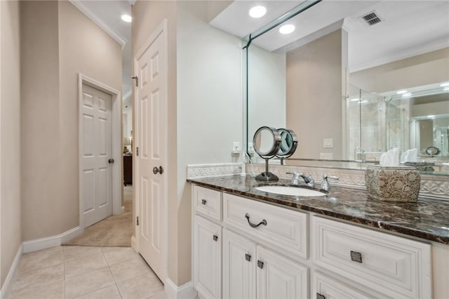 bathroom featuring tile patterned flooring, vanity, a shower with shower door, and crown molding