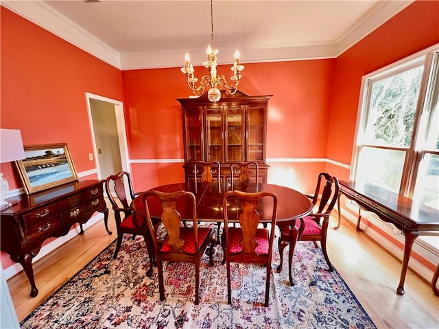 dining area featuring ornamental molding, light hardwood / wood-style flooring, and an inviting chandelier