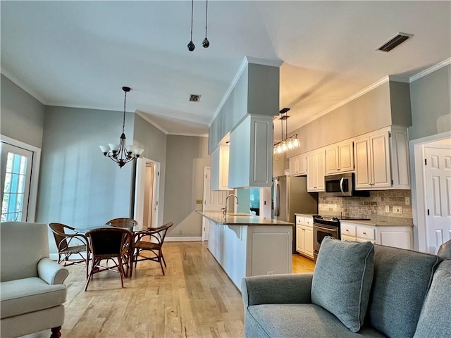 145 Shore Rush Dr, Saint Simons Island, GA 31522 - kitchen with open floor plan, appliances with stainless steel finishes, a chandelier, crown molding, and light wood-style floors