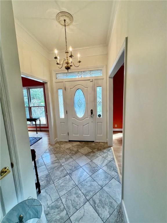 145 Shore Rush Dr, Saint Simons Island, GA 31522 - foyer entrance with crown molding, a chandelier, and light marble finish flooring