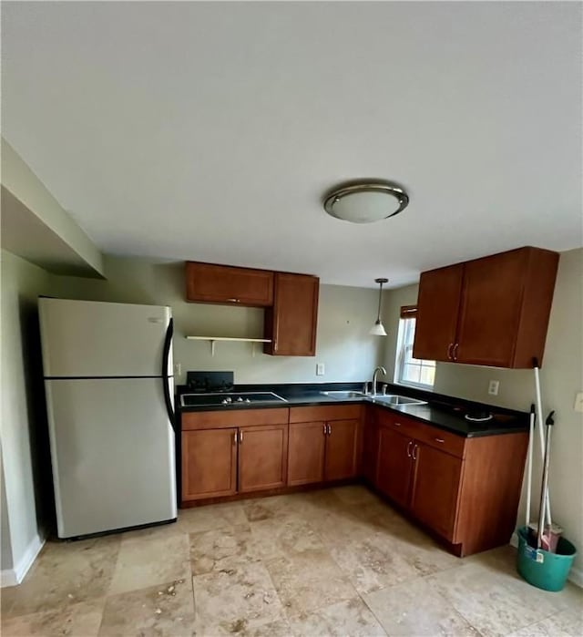 145 Shore Rush Dr, Saint Simons Island, GA 31522 - kitchen with freestanding refrigerator, dark countertops, black cooktop, brown cabinets, and hanging light fixtures