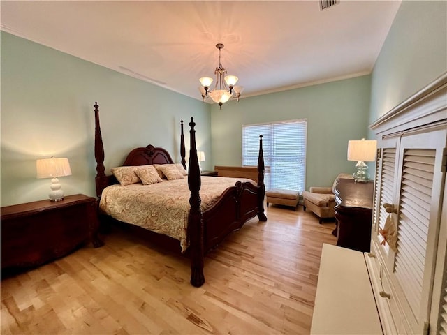 bedroom featuring light hardwood / wood-style floors, crown molding, and a chandelier