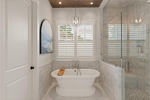 bathroom with a notable chandelier, tile walls, and plus walk in shower