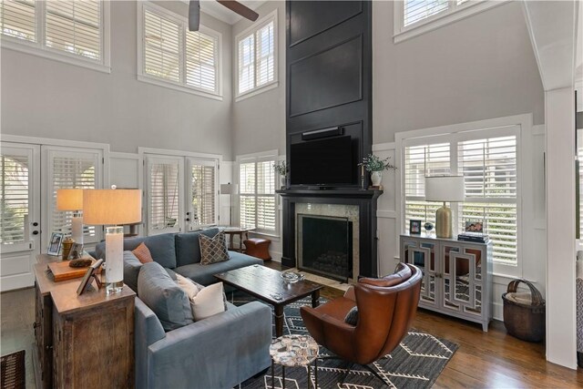 living room featuring a high ceiling, dark hardwood / wood-style flooring, a large fireplace, and ceiling fan