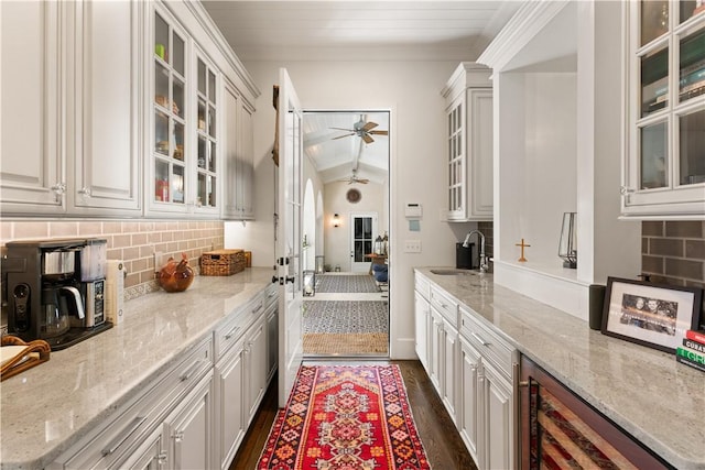 kitchen with white cabinetry, sink, light stone countertops, dark wood-type flooring, and vaulted ceiling