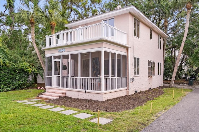 4206 Tenth St, Saint Simons Island, GA 31522 - back of property featuring a balcony, a sunroom, stucco siding, and a lawn