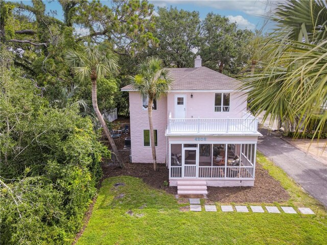 4206 Tenth St, Saint Simons Island, GA 31522 - rear view of property with a sunroom, a balcony, stucco siding, a lawn, and a chimney
