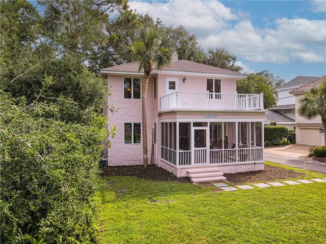 4206 Tenth St, Saint Simons Island, GA 31522 - rear view of property featuring a balcony, a sunroom, stucco siding, a yard, and a shingled roof