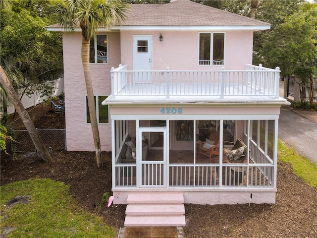 4206 Tenth St, Saint Simons Island, GA 31522 - rear view of property with a balcony, stucco siding, roof with shingles, and a sunroom
