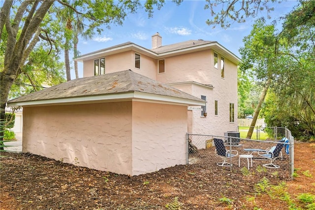 4206 Tenth St, Saint Simons Island, GA 31522 - view of side of property featuring stucco siding, a chimney, and cooling unit