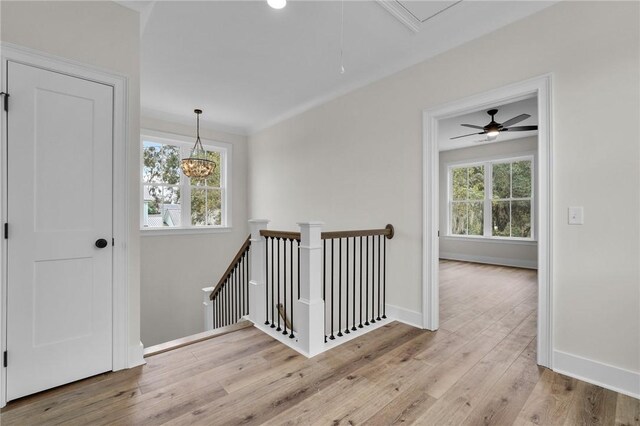 hallway featuring an upstairs landing, attic access, baseboards, and wood finished floors