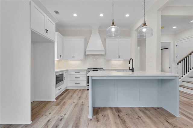 kitchen with premium range hood, visible vents, tasteful backsplash, stainless steel appliances, and light countertops