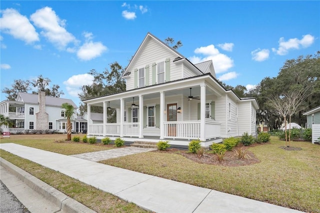 country-style home featuring a front yard, metal roof, covered porch, and ceiling fan