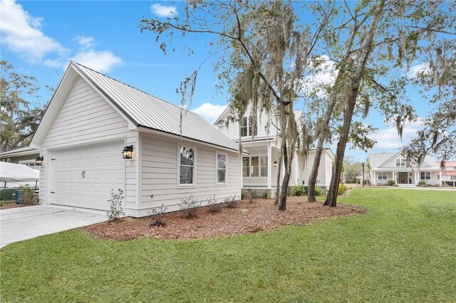 view of home's exterior featuring a lawn, an attached garage, metal roof, and driveway