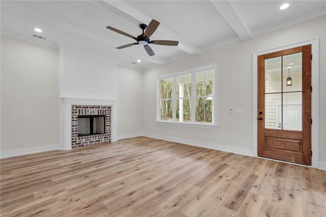 unfurnished living room featuring visible vents, baseboards, beam ceiling, light wood-style flooring, and a fireplace