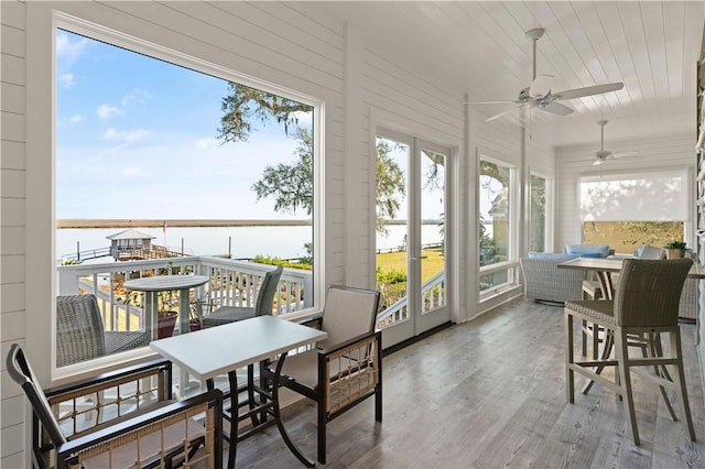 sunroom / solarium featuring a water view and ceiling fan