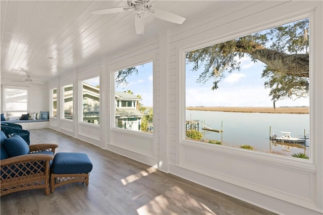 sunroom featuring ceiling fan and a water view