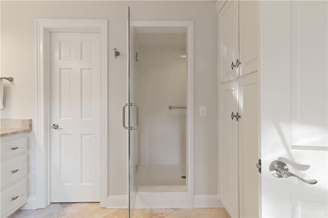 bathroom featuring tile patterned floors, a shower with door, and vanity