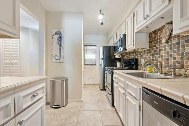 kitchen with sink, light tile patterned floors, stainless steel appliances, white cabinets, and tile countertops