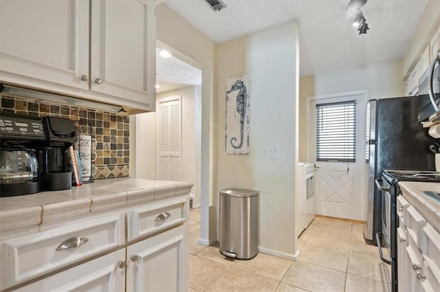 kitchen featuring white cabinetry, light tile patterned floors, appliances with stainless steel finishes, tile counters, and backsplash