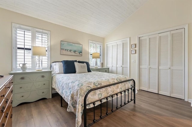 bedroom featuring multiple closets, wood-type flooring, vaulted ceiling, and wood ceiling