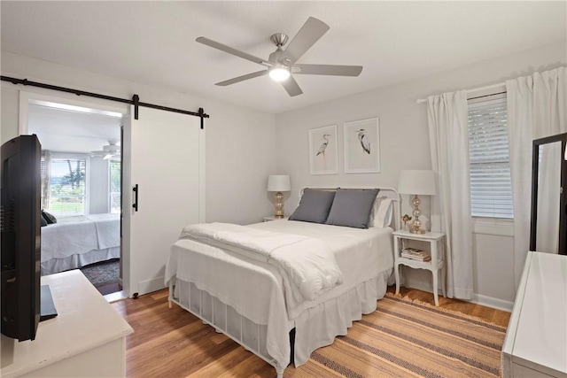 1152 Julienton Lndg NE, Townsend, GA 31331 - bedroom with a barn door, light wood-style flooring, and a ceiling fan