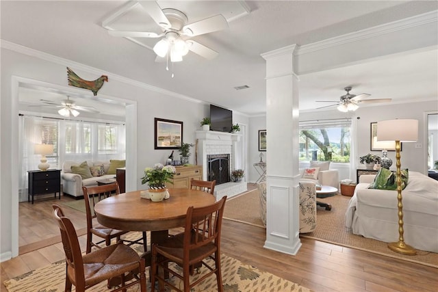 1152 Julienton Lndg NE, Townsend, GA 31331 - dining room featuring a ceiling fan, decorative columns, a brick fireplace, light wood-style floors, and ornamental molding