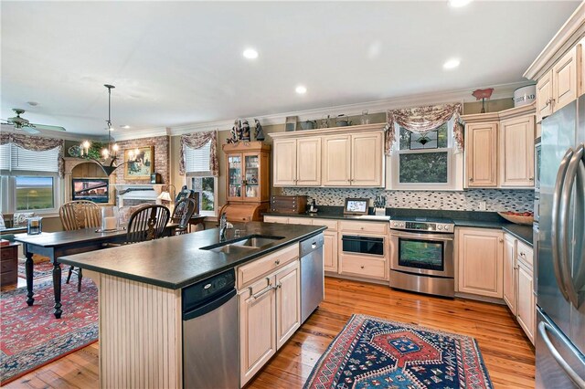 kitchen featuring a kitchen island with sink, a wealth of natural light, crown molding, and stainless steel appliances