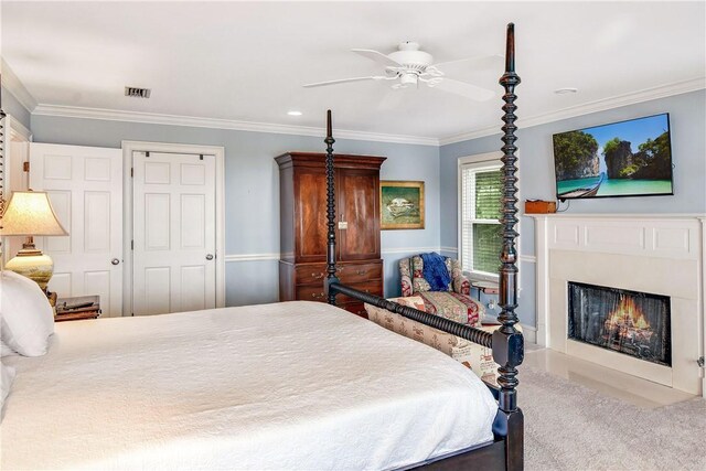 carpeted bedroom with ceiling fan, crown molding, and a closet