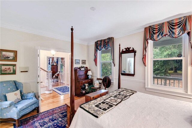 bedroom featuring wood-type flooring, multiple windows, and crown molding