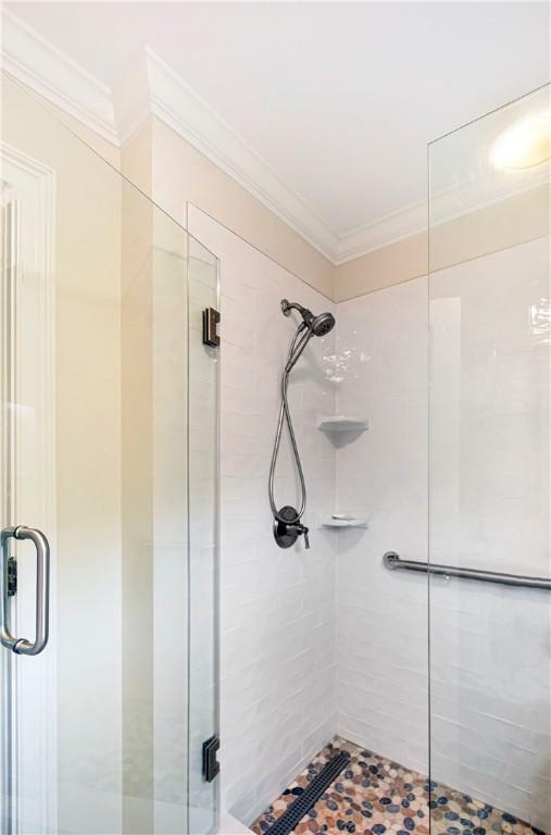 bathroom featuring a shower with door and ornamental molding