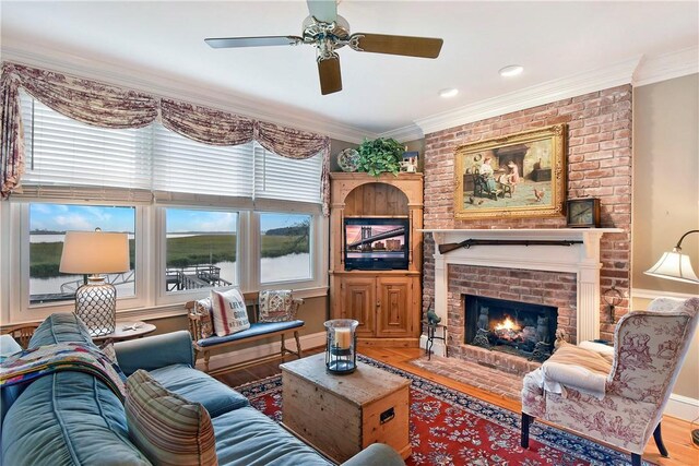 living room featuring a fireplace, ceiling fan, wood-type flooring, and ornamental molding