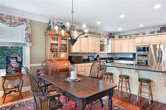 dining area with sink, ornamental molding, and dark wood-type flooring