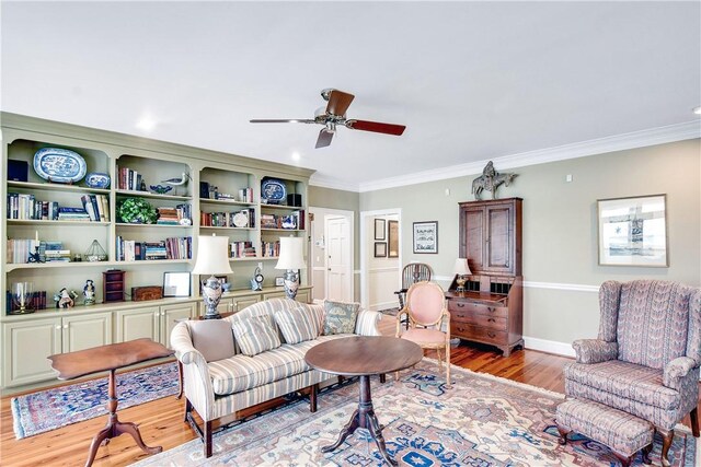 living room with ceiling fan, ornamental molding, and light wood-type flooring