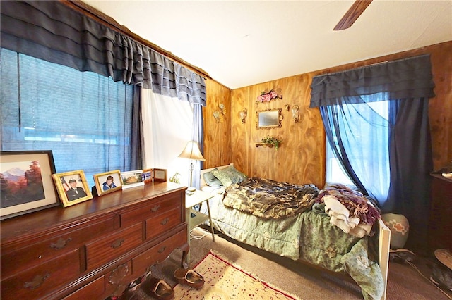 carpeted bedroom with ceiling fan and wooden walls