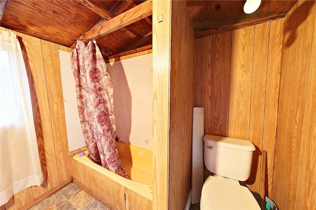 bathroom featuring shower / bath combination with curtain, toilet, lofted ceiling, and wooden walls